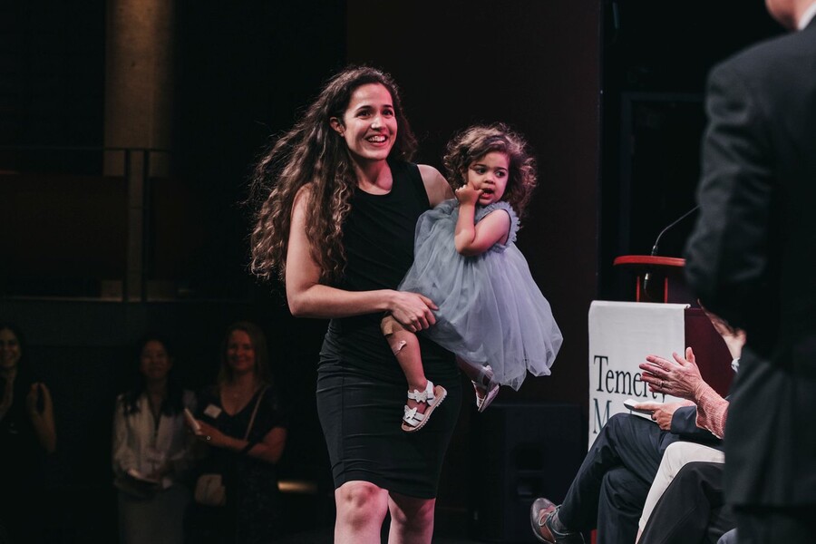 Woman crossing a graduation stage holding her child